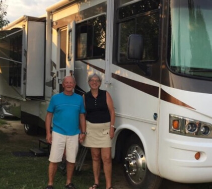Joyce (right) and husband (left) in front of their RV called 