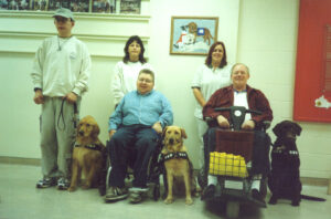 A group of people posing with their dogs at graduation day at the Lions Foundation of Canada.