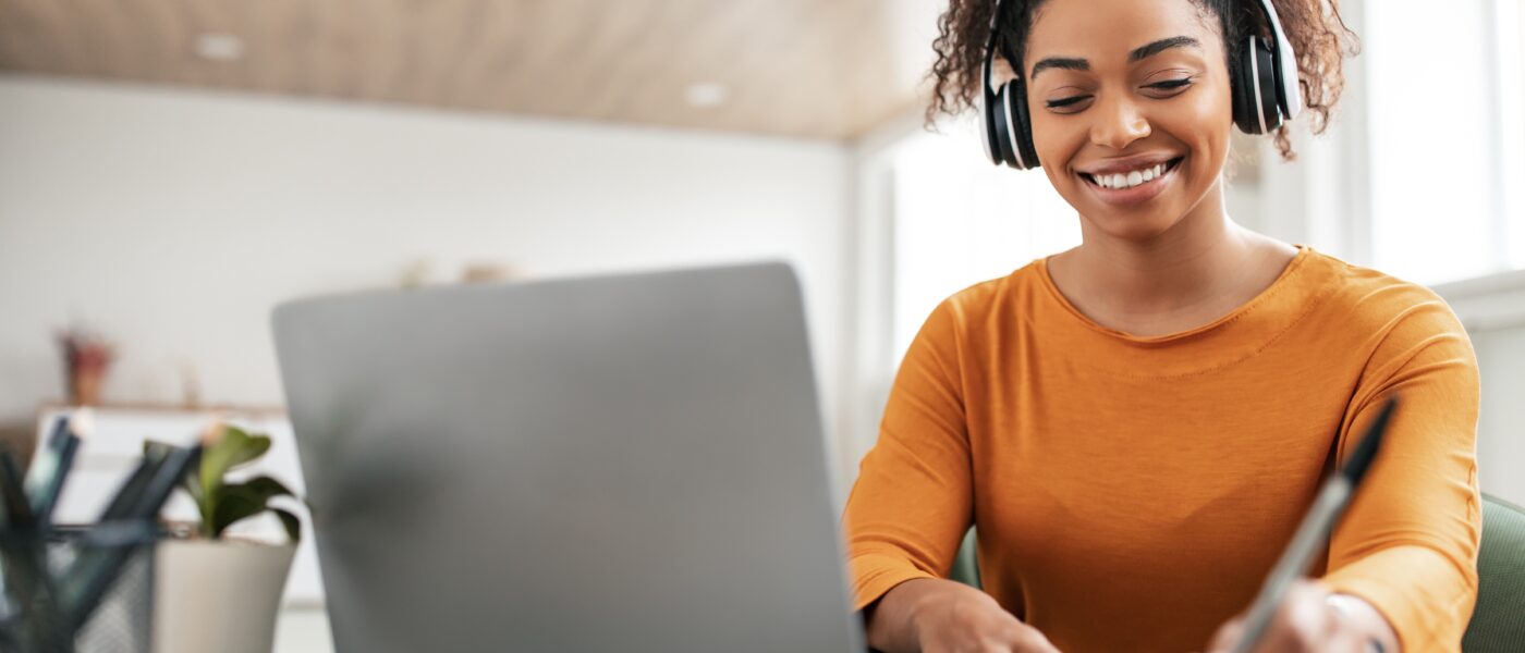 Young woman sitting in front of her laptop taking notes.